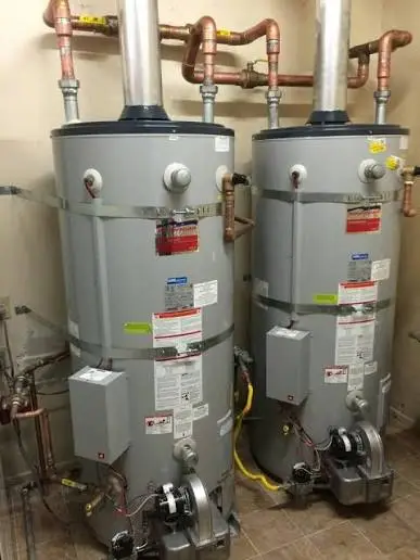 Two commercial gas storage water heaters installed side by side in a mechanical room
