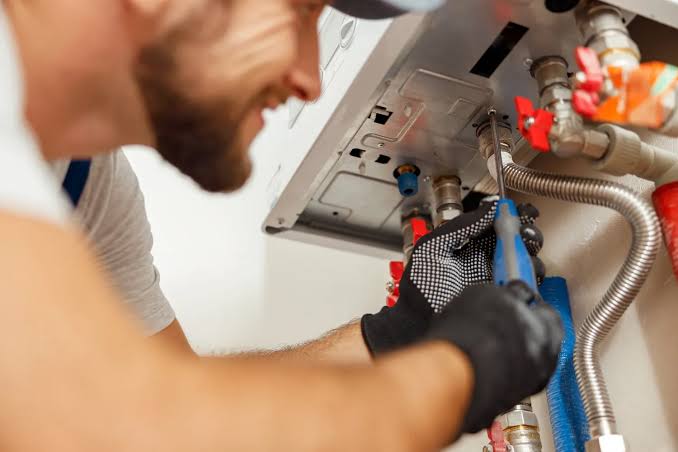 Technician installing commercial water heater connections in a Harrisburg PA building